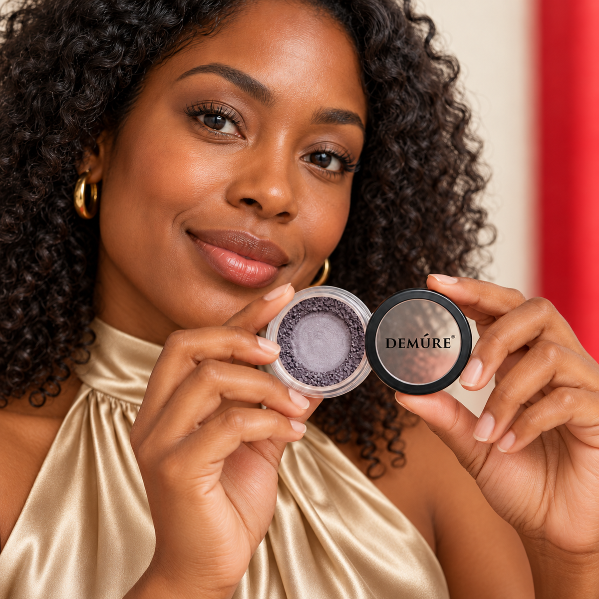 An adult model wearing champagne satin high-neck holds Demure Mineral Eyeshadow — Castle Rock. Pictured variant: Castle Rock.